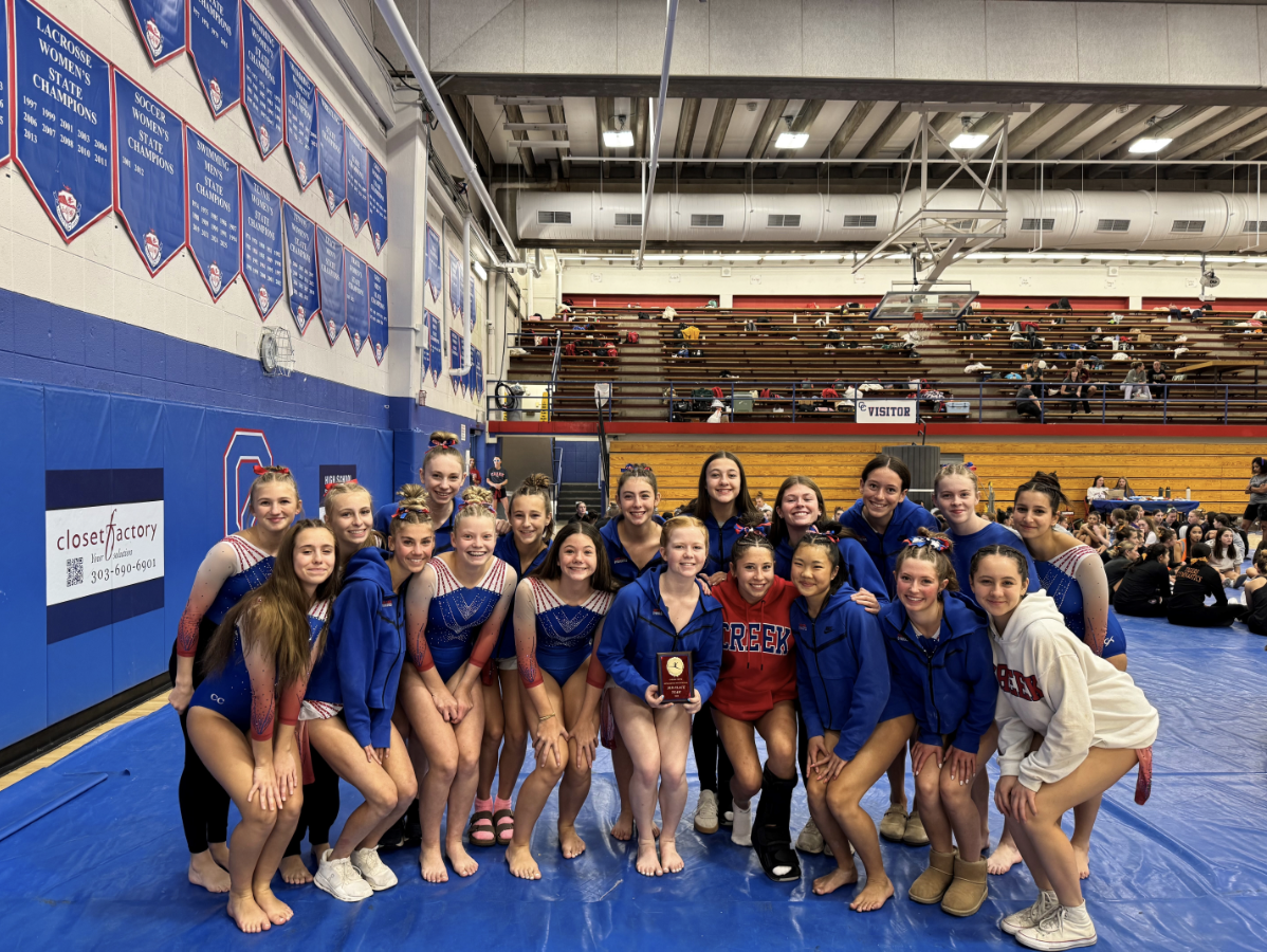 Cherry Creek Bruins gymnastics team celebrating with an award plaque in the gym