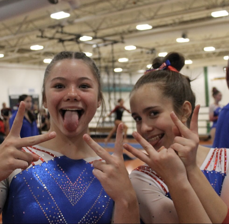 Two Bruins gymnasts posing playfully in competition leotards